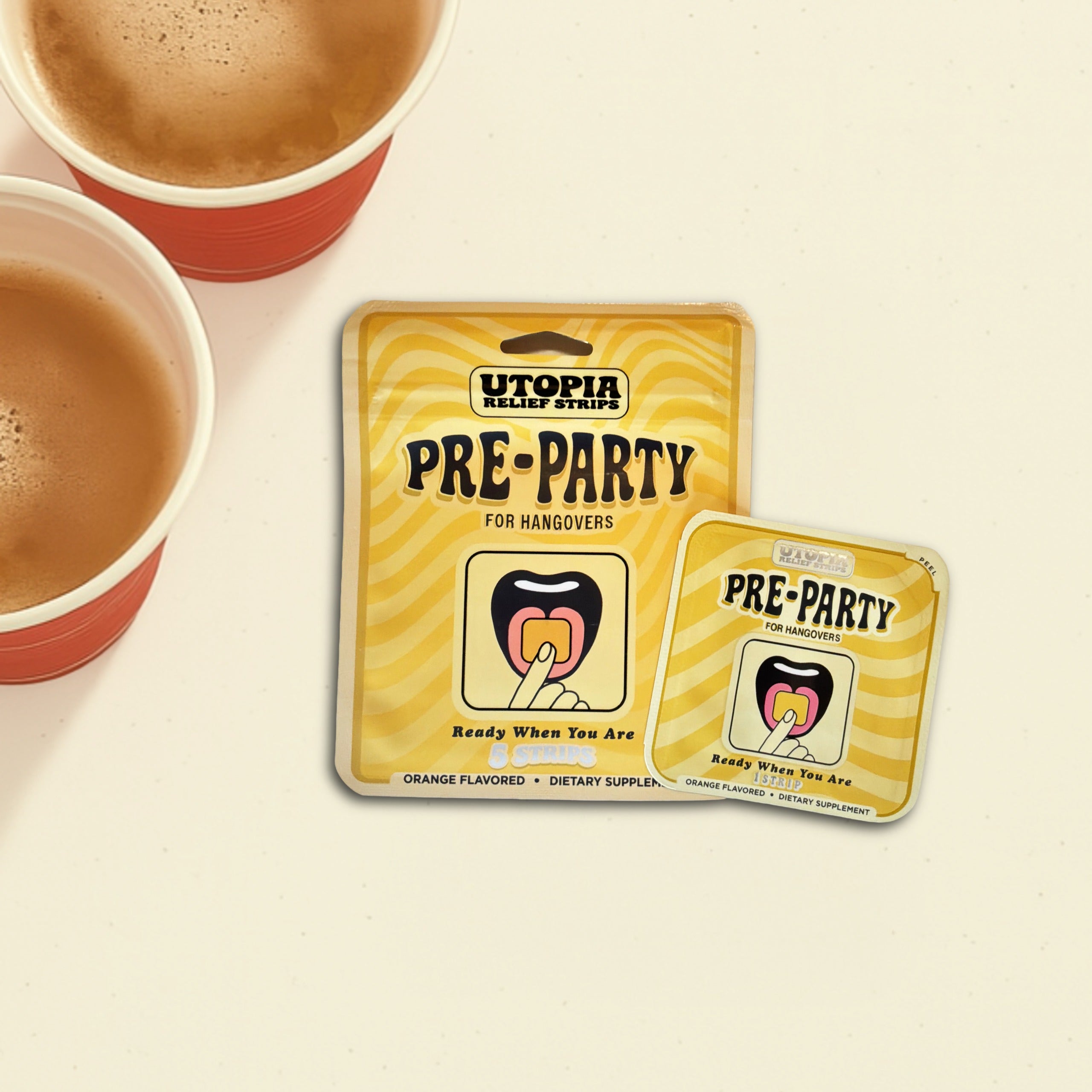 Two yellow Utopia Pre-Party oral supplement packets are displayed on a cream-colored surface next to two red solo cups. The packets feature a wavy yellow and white striped pattern with black text and an illustration of a tongue touching an oral strip.