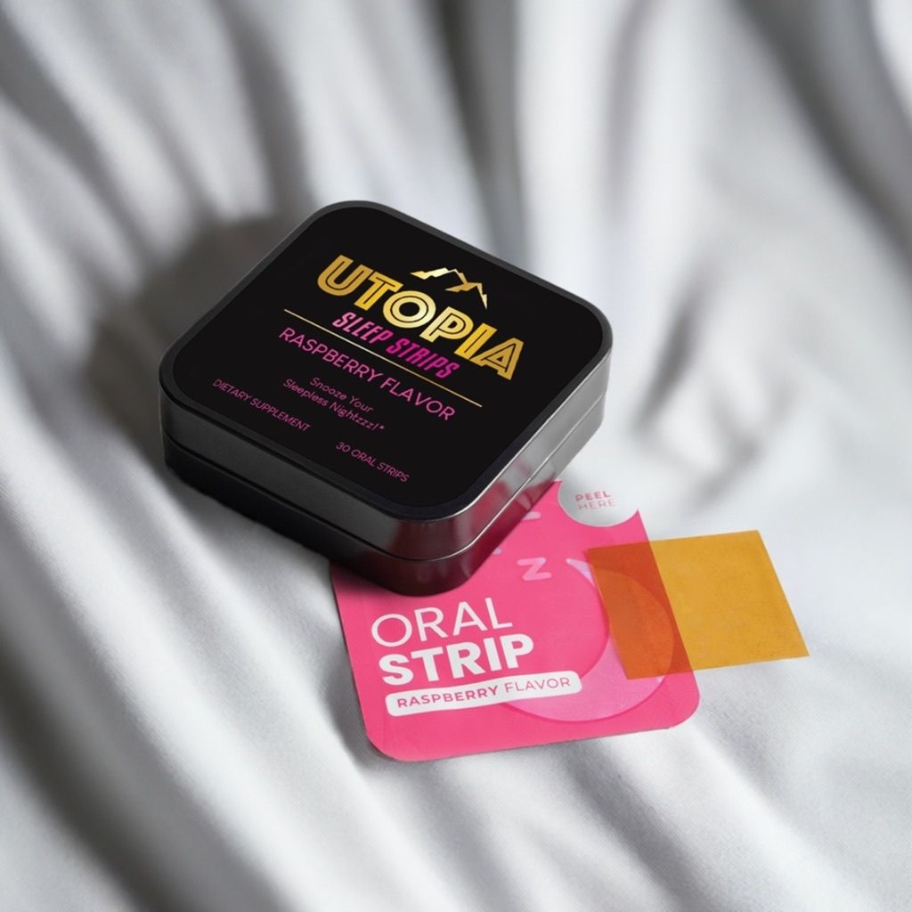 Utopia Sleep Strips raspberry flavor 30-count box and oral strip on a soft white fabric background, highlighting the premium packaging and dissolvable strip for convenient nighttime use.